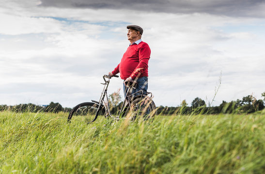 Senior man with bicycle in rural landscape