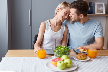 Happy couple embracing at table during breakfast