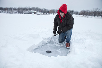 Fototapeta na wymiar A middle aged man ice fishing on a lake in Minnesota during the winter