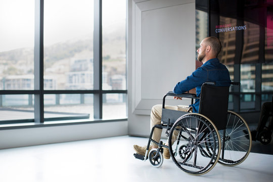 Man in wheelchair looking out of window in office