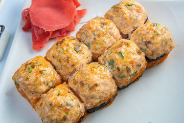 Baked rolls with scallop , spicy sauce, cream cheese and mango with rice on white plate with gold border. Asian menu