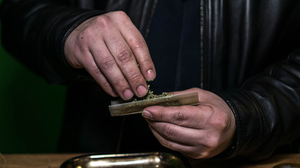 A Man Placing Cannabis In A Smoking Paper