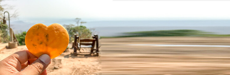 Yellow heart-shaped leaves on the hands of men with a natural background.