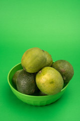 fresh limes or lemons in green bowl monochromatic on green background 