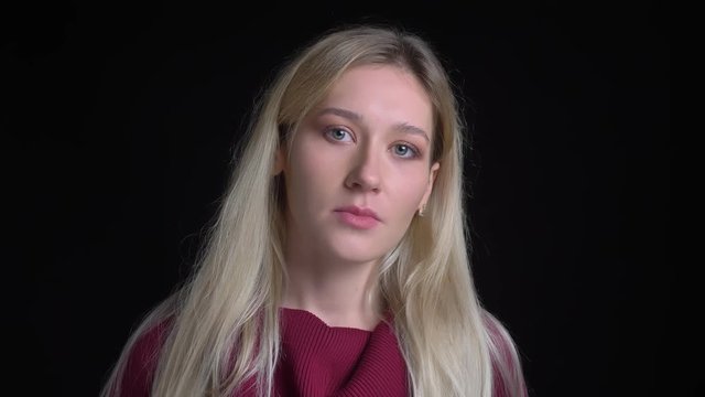 Closeup shoot of young pretty caucasian female with long blone hair looking straight at camera with contemplation