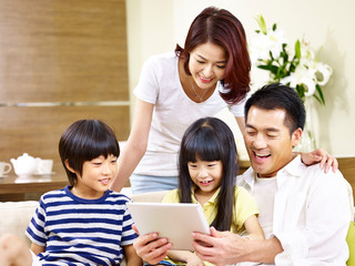 asian family with two children using digital tablet together
