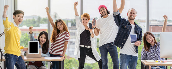 Banner and web page of Portrait Group Of Asian and Multiethnic Business people in happy action and celebrate with technology device themself when project is completed in the modern workplace © THANANIT