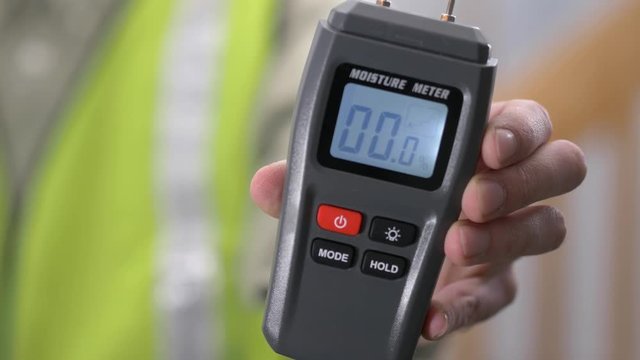 Contractor worker showing his moisture meter device to find water leaks behind walls and humidity in wood.