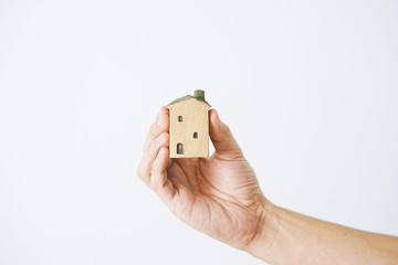 Hand holding small house on white background.