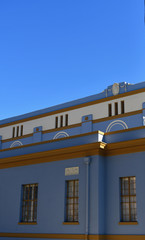 Fototapeta na wymiar Side view of tall building with rectangular windows reflecting bright blue sky