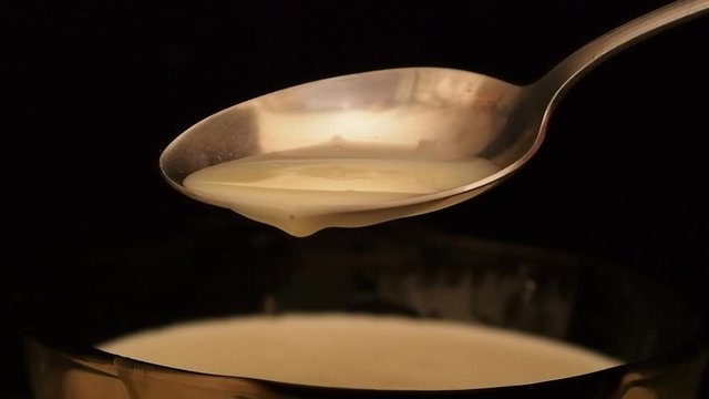 Iron spoon with condensed milk on a dark background