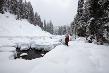 Blonde Caucasian Girl is enjoying the beautiful Canadian Winter Scenery during a snowy day. Taken in Alexander Falls, near Whistler and Squamish, North of Vancouver, BC, Canada.