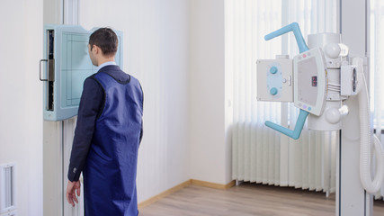 lateral view of a female radiologist doing the paranasal sinuses X-ray to a male patient in examination room
