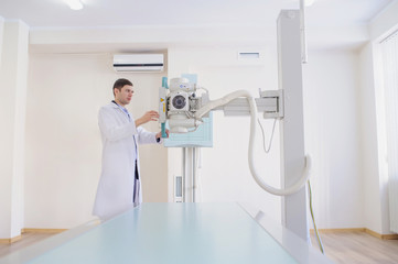  lateral view of a male radiologist adjusting the X-ray machine in examination rom
