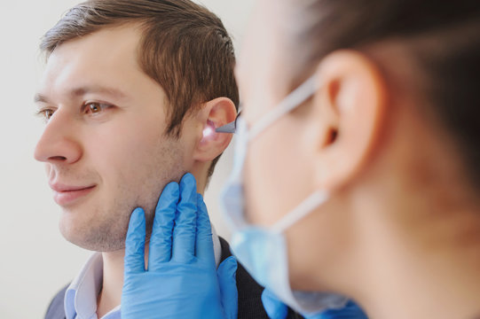 close up photo of a female otolaryngologist examining the ear of a male patient