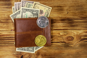 Wallet with american dollars bills and bitcoins on wooden background