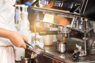Bartender are making coffee by coffee machine.
