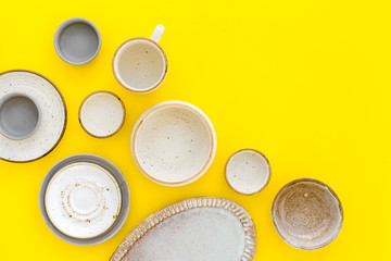 Ceramic tableware pattern. Empty plates and mugs on yellow background top view space for text