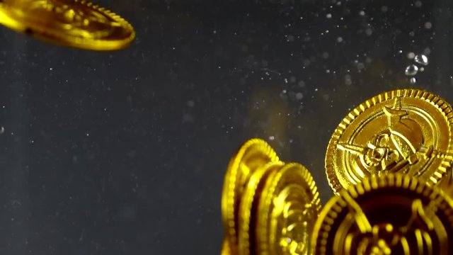 golden coins are sinking inside water of ocean, close-up view of underwater shot