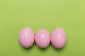 pink easter eggs in nest on green pastel color background with space.