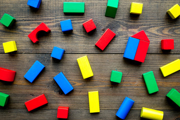 Children background. Wooden building blocks for developing and entertainment on dark wooden background top view
