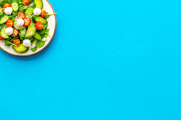 Healthy lunch. Fresh vegetable salad on blue background top view copy space