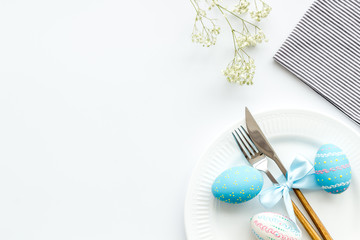 Easter table decoration in blue colors. Plate, cutlery, painted eggs and dry flower branch,...