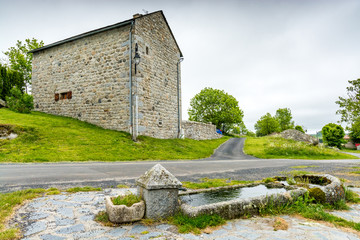 Fototapeta na wymiar former drinking trough in front of a stone building in a village of Aubrac