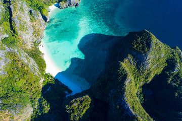View from above, stunning aerial view of Koh Phi Phi Lee with the beautiful beach of Maya Bay bathed by a turquoise clear water and amazing ridges of limestone mountains.