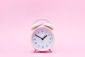 Pink ringing alarm clock on pink background