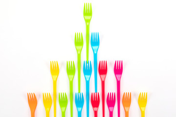 Many color plastic forks on a bright background