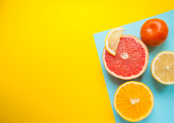 Flat lay of cut ripe juicy grapefruit, lemon and orange on blue and yellow background with copyspace. Citrus pattern.