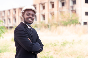 African engineering man stand up and smiling with building construction background