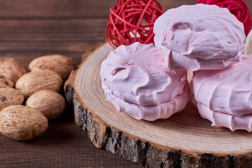 Three zephyrs with raspberries on a wooden stand next to nuts and various decorative elements on...