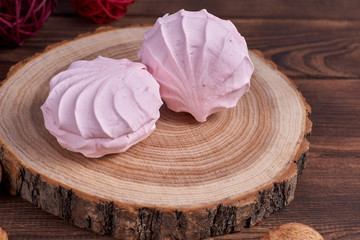 Two zephyrs with raspberries on a wooden stand next to nuts and various decorative elements on the dark wooden background. Close-up