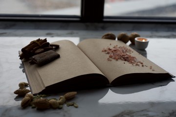 Vintage book with empty pages, near the window, with candle and spices