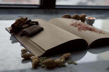 Vintage book with empty pages, near the window, with candle and spices