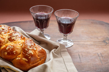 Challah bread with two glasses of red wine on wooden table, copy space