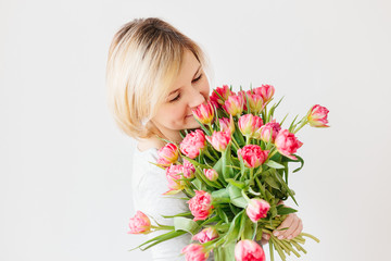 Happy attractive middle-aged blonde woman with a bouquet of red pink white tulips
