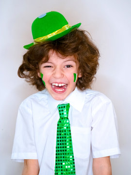 Hispanic child boy having fun during Saint Patrick celebrations over a light background. I am smiling a boy with a green shamrock and Irish flag on my cheek. Patrick's Day celebrations.