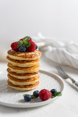 Delicious pancakes, with fresh blueberries, strawberries and honey on a white background, close up. Copy space. Breakfast concept