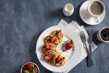 pancakes with strawberry and chocolate sauce with coffee on dark background. Copy space. Flat lay, top view