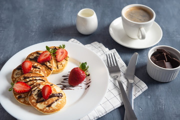 Homemade pancakes with strawberry and chocolate sauce with coffee on dark background. Breakfast, nutrition concept. Copy space. Side view