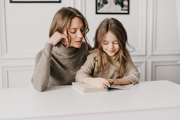  beautiful young mother doing homework with her little daughter