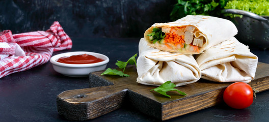 Delicious shawarma sandwich on a black background. Burritos wraps with grilled chicken and vegetables, greens. Fajitas, pita bread. Traditional Middle Eastern appetizer. Healthy food. Mexican cuisine