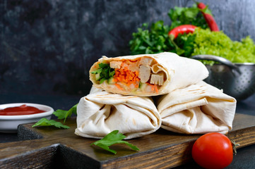 Delicious shawarma sandwich on a black background. Burritos wraps with grilled chicken and vegetables, greens. Fajitas, pita bread. Traditional Middle Eastern appetizer. Healthy food. Mexican cuisine.