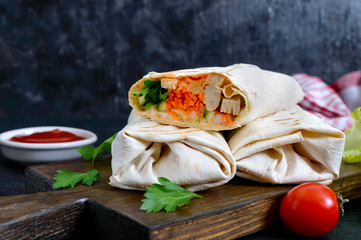 Delicious shawarma sandwich on a black background. Burritos wraps with grilled chicken and vegetables, greens. Fajitas, pita bread. Traditional Middle Eastern appetizer. Healthy food. Mexican cuisine.