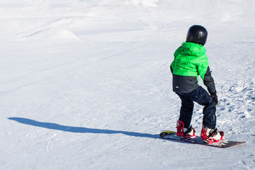 Fototapeta na wymiar Kid on snowboard in winter sunset nature. Sport photo with edit space