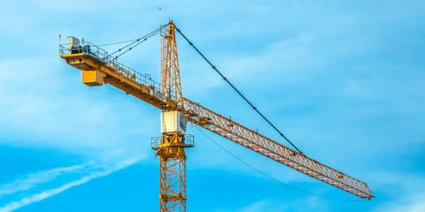 Huge construction tower crane and cloudy blue sky