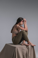 Long-haired cute young model with body art in a beige bra looking calm